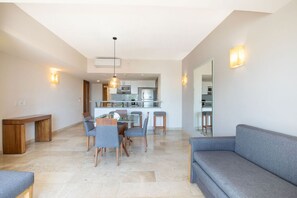 A modern living room with a dining area, a sofa, and a kitchen in the background.