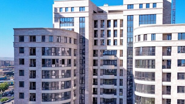 Um edifício com várias andares, fachada curva, janelas grandes e design arquitetônico moderno.