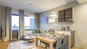 Una habitación de hotel moderna con comedor, sofá, cafetera y vistas a la ciudad.