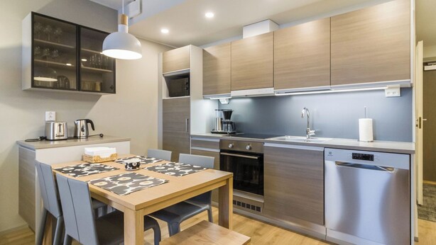 Una cocina moderna con electrodomésticos de acero inoxidable, un comedor con mesa y sillas de madera, y un horno empotrado.