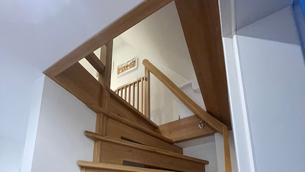 Een houten trap met een leuning en een plateau.