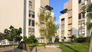 A courtyard with modern buildings, a playground, and a grassy area with colorful circular patterns. - Modern 2BR Retreat | Pool, Wi-Fi, AC & Prime Location, 10 Min from Everything (Puerto Vallarta)