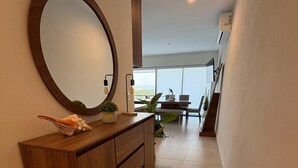 A modern hallway with a wooden console, a large mirror, and a view of a dining area with a table and chairs. - Modern 2BR Retreat | Pool, Wi-Fi, AC & Prime Location, 10 Min from Everything (Puerto Vallarta)