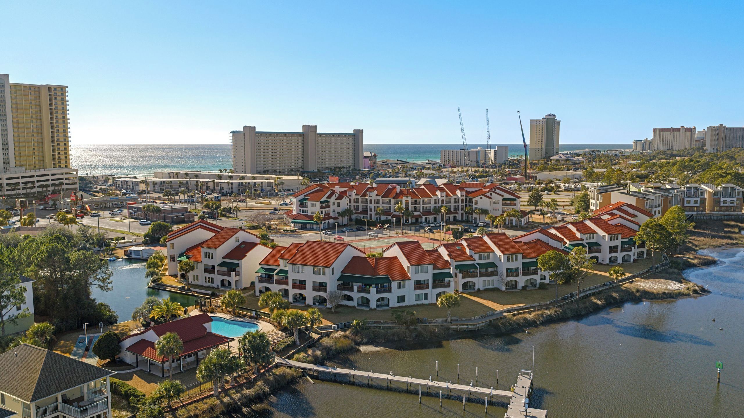 Un hotel costero con varias construcciones, un puerto deportivo y vistas al océano.