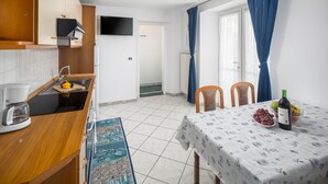 A compact kitchen with a sink, a coffee maker, and a small dining area with a table set for two. - Amazing apartment in Zambratija with WiFi (Zambratija)