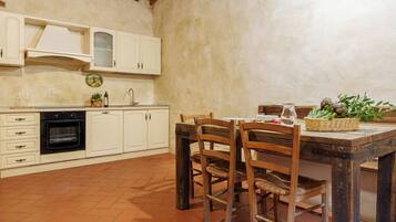 A rustic kitchen with white cabinets, a black oven, and a wooden dining table with chairs.
