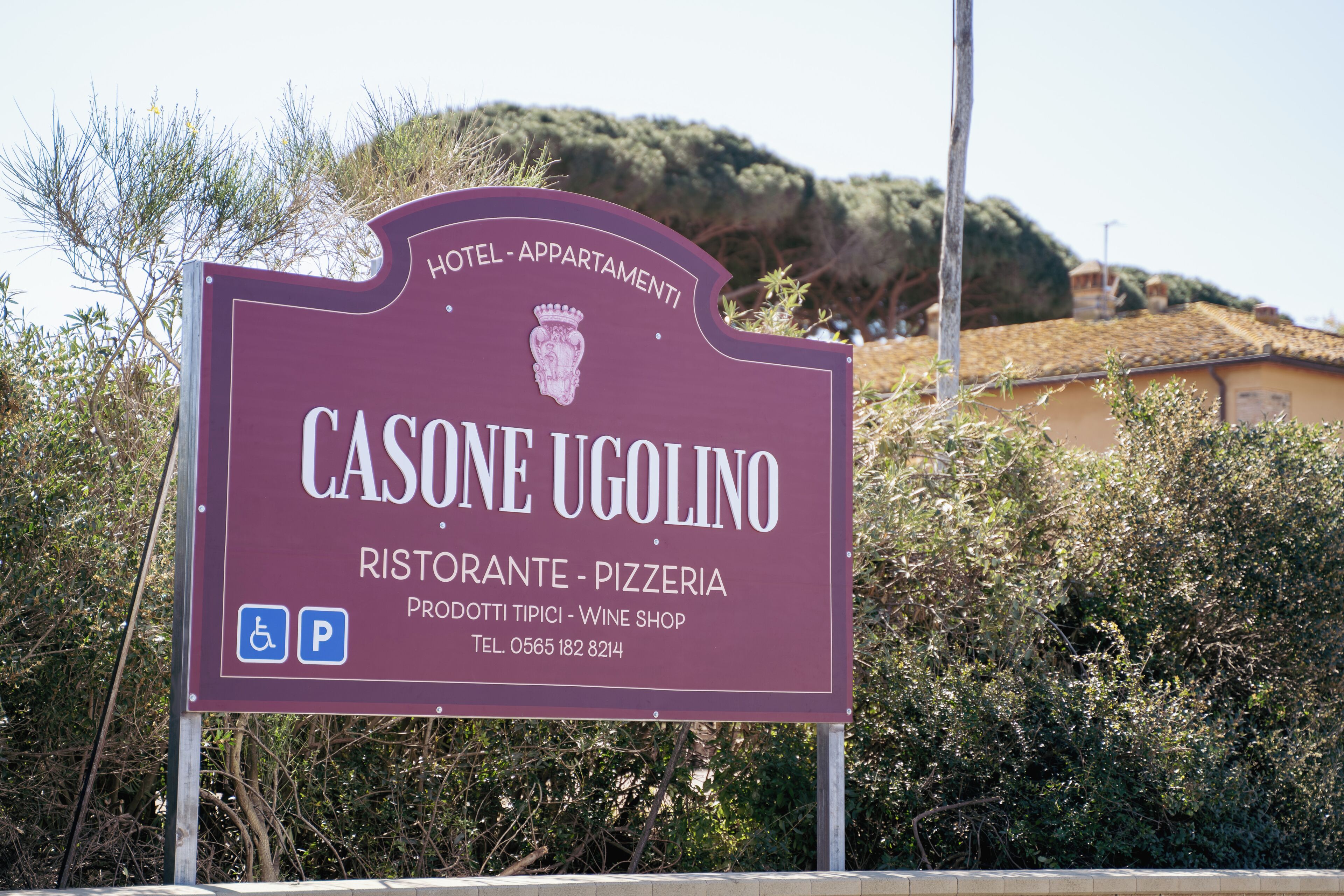 Señal para el hotel Casone Ugolino, con servicios que incluyen restaurante, pizzería y tienda de vinos.