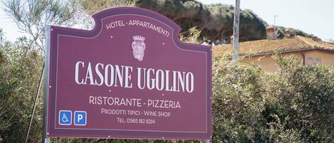 Señal para el hotel Casone Ugolino, con servicios que incluyen restaurante, pizzería y tienda de vinos.