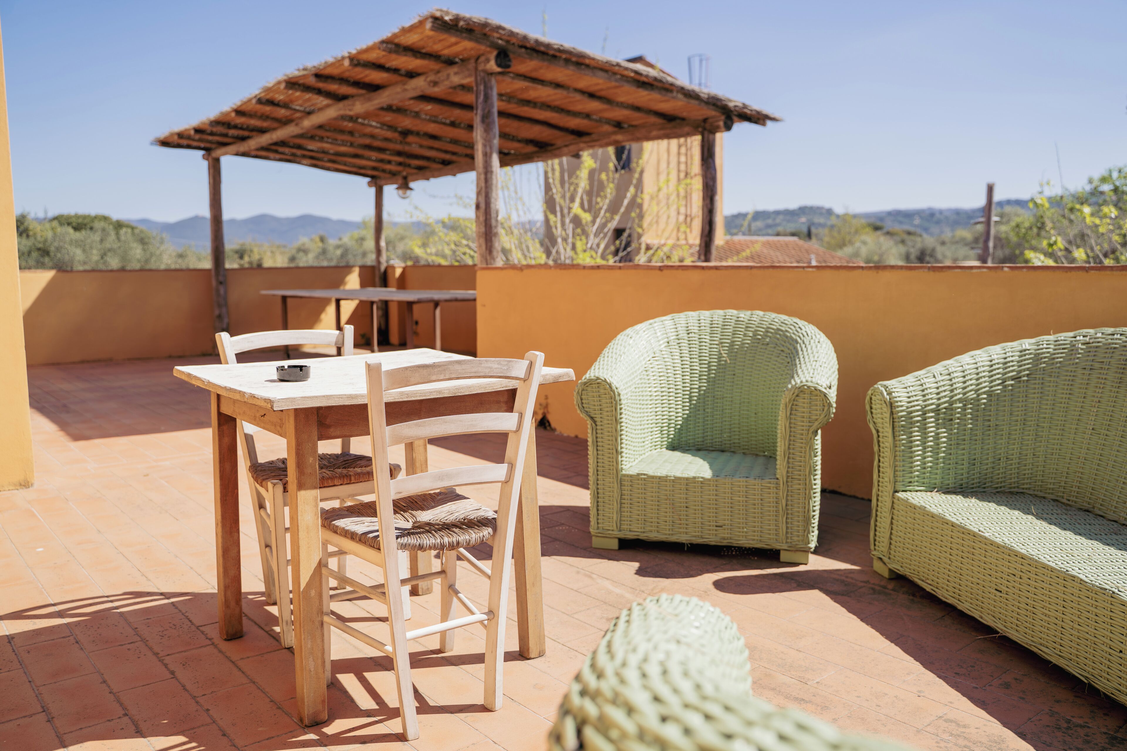 A patio with a table, chairs, and wicker furniture.