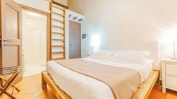 Una camera da letto con un letto, una scala in legno, una porta e un comodino.