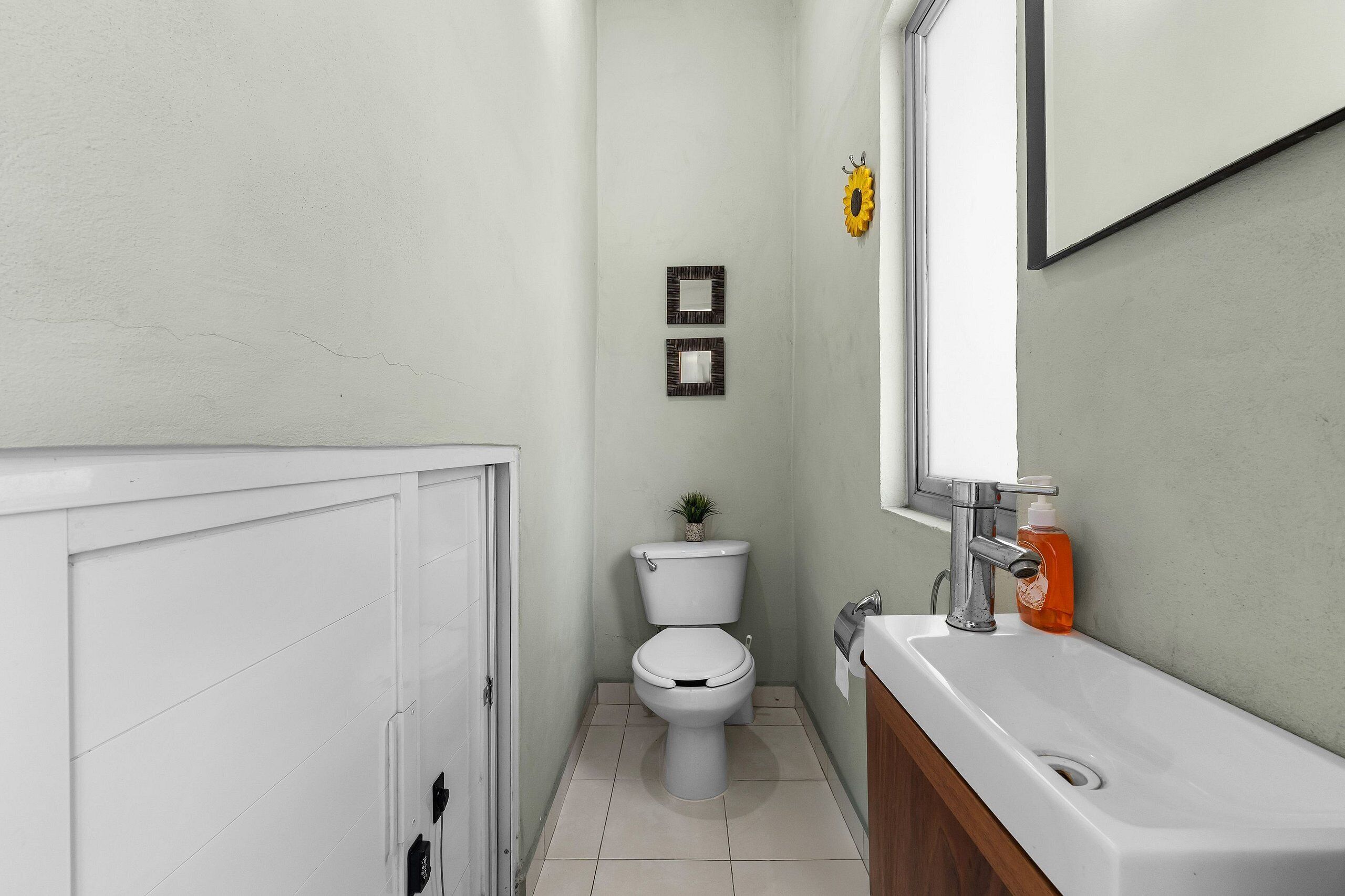 Un bagno con il water, un lavandino e due quadri appesi alla parete.