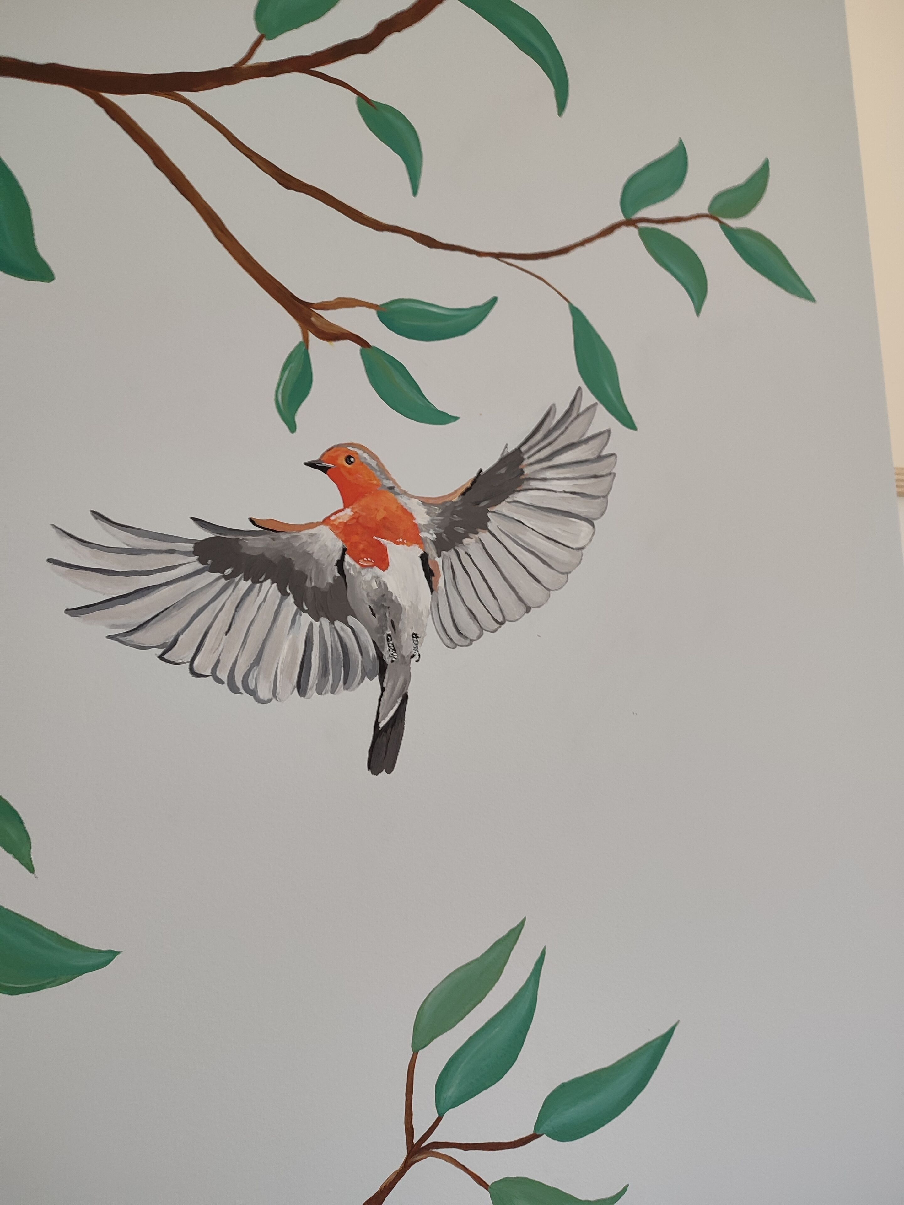 Een vliegende vogel met groene bladeren en een bruine tak.