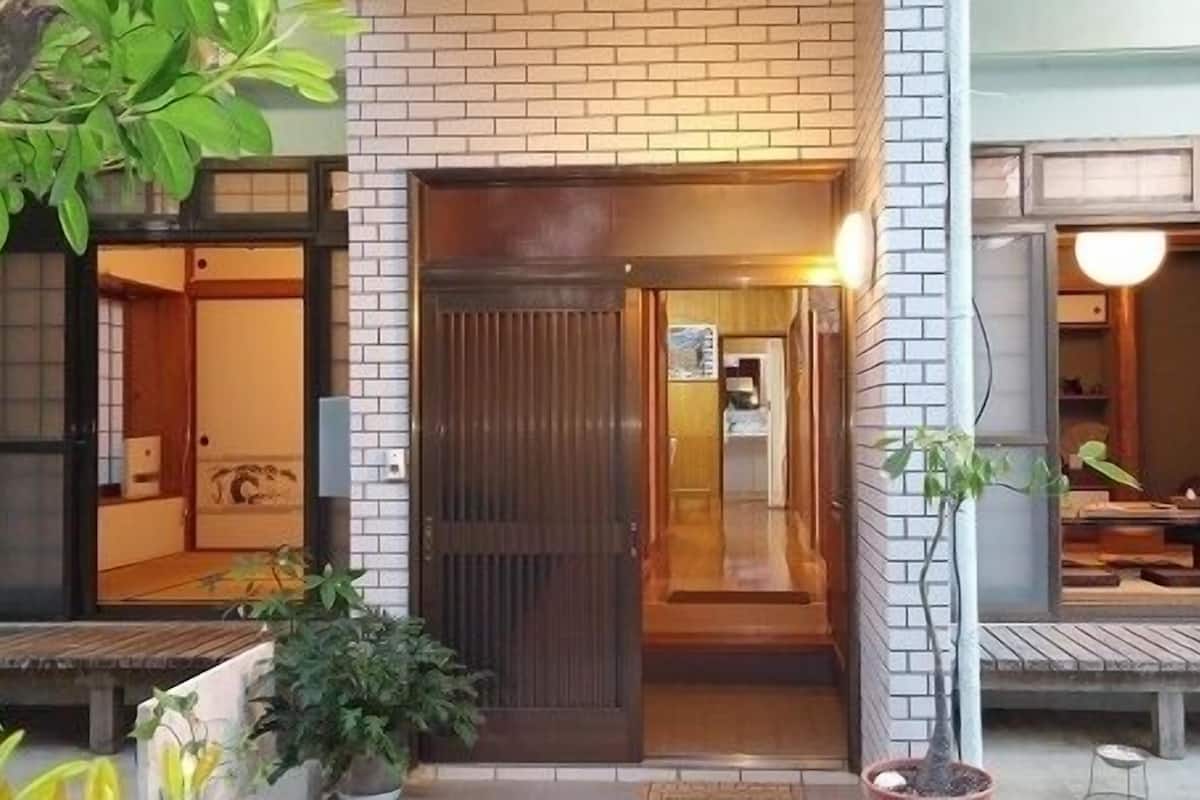 A building with a brick facade, a wooden door, and a small porch area.