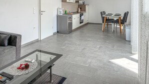 A modern apartment with a glass dining table, a kitchen with white cabinets, and a grey tiled floor. - 2 bedroom nice apartment in Cizici (Cizici)