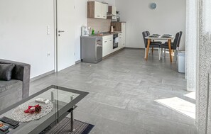 A modern apartment with a glass dining table, a kitchen with white cabinets, and a grey tiled floor. - 2 bedroom nice apartment in Cizici (Cizici)