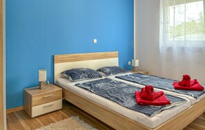 A double bed with a wooden headboard, two bedside tables with lamps, a fluffy rug, and a window with floral curtains. - 2 bedroom nice apartment in Cizici (Cizici)