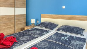 A bed with a nautical-themed bedspread, a wooden headboard, and a nightstand with a lamp. - 2 bedroom pet friendly apartment in Cizici (Cizici)