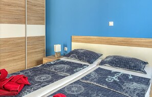 A bed with a nautical-themed bedspread, a wooden headboard, and a nightstand with a lamp. - 2 bedroom pet friendly apartment in Cizici (Cizici)