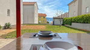 A table set with plates, cutlery, and a bowl in a courtyard with a view of buildings and a body of water. - 2 bedroom pet friendly apartment in Cizici (Cizici)
