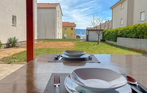 A table set with plates, cutlery, and a bowl in a courtyard with a view of buildings and a body of water. - 2 bedroom pet friendly apartment in Cizici (Cizici)