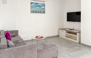 A living room with a grey sofa, a glass coffee table, a white entertainment unit, and a flat-screen TV. - Amazing apartment in Cizici with house sea view (Cizici)