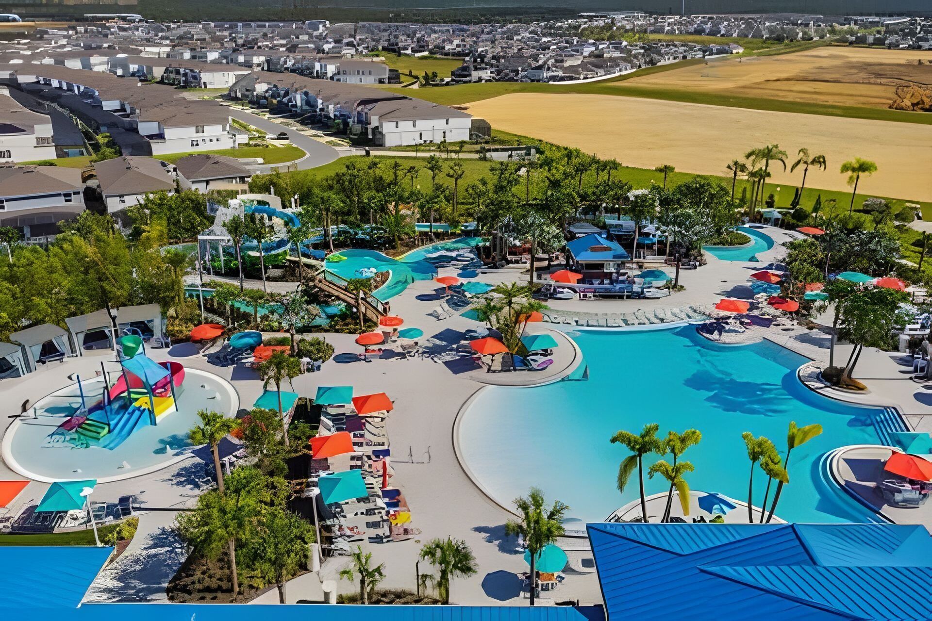 Ein Resort mit einem großen Schwimmbecken, Wasserrutschen und mehreren Liegebereichen mit Sonnenschirmen.
