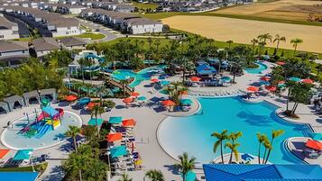 Um resort com uma piscina grande, toboáguas e várias áreas de estar com guarda-sóis.