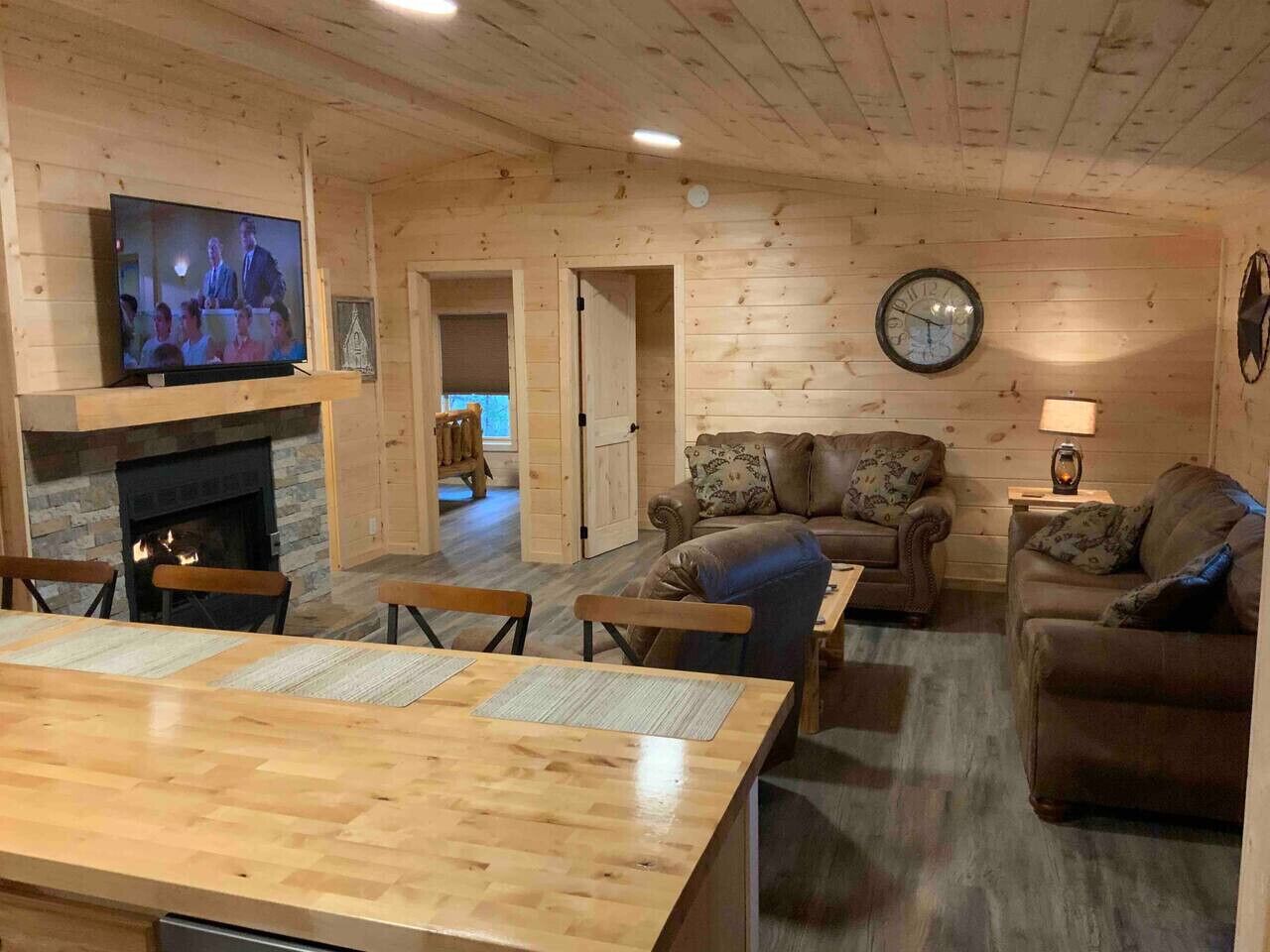 A cozy living room with a fireplace, wooden walls, a television, and comfortable seating.