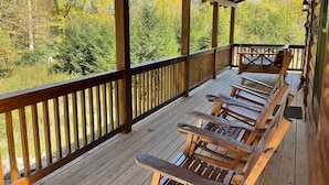 Um deck de madeira com bancos e guarda-corpo com vista para uma área arborizada.