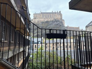 Uma varanda com vista para um edifício histórico de pedra ao fundo.