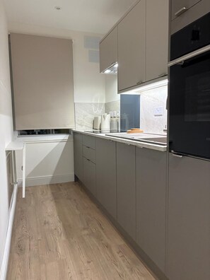 A modern kitchen with grey cabinets, a white countertop, and a black oven. - Edinburgh castle view apartment newly renovated (4 people) (Edinburgh)