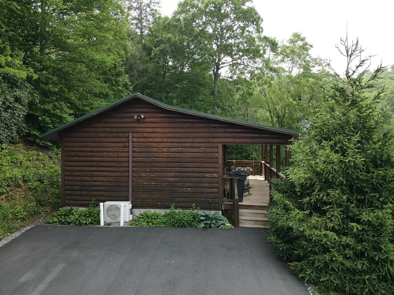 Eine Holzhütte mit überdachter Veranda, umgeben von dichtem Grün.