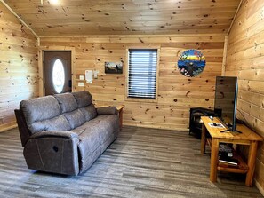 Ein gemütliches Blockhaus-Interieur mit einer Liegesofa, einem Holztisch und einem Kamin.