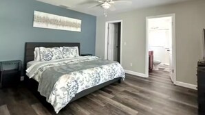 Un dormitorio con cama, ventilador de techo y puerta que da a un baño.