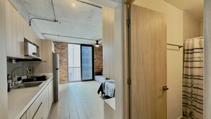 A modern apartment with a kitchen, a dining area, a balcony, and a bathroom.
