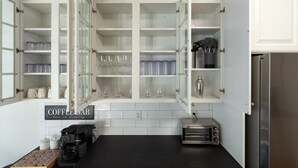 A kitchen with open cabinets, a coffee machine, and a toaster oven. - Golfer Paradise - Pool, Sauna, Hot Tub, Putting Green and More! (Pinehurst)