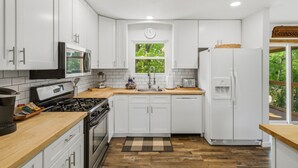 A modern kitchen with white cabinets, a stove, a microwave, and a refrigerator. - Stylish Knoxville Retreat w/ Media Room & Patio (Knoxville)