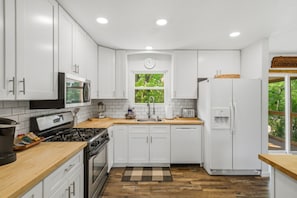 A modern kitchen with white cabinets, a stove, a microwave, and a refrigerator. - Stylish Knoxville Retreat w/ Media Room & Patio (Knoxville)