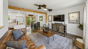 A spacious living room with a leather sofa, a dining area, a kitchen, and a TV mounted on the wall. - Stylish Knoxville Retreat w/ Media Room & Patio (Knoxville)