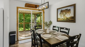 A dining area with a table set for four, a framed landscape painting, and a sign above the door reading 'Great Smoky Mountains Tennessee.' - Stylish Knoxville Retreat w/ Media Room & Patio (Knoxville)