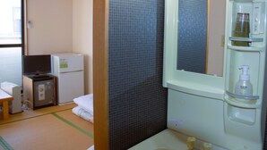A bathroom with a sink, mirror, and toiletries. There is a television and a small refrigerator in the corner. - Villa Iwasawa (Hirono)