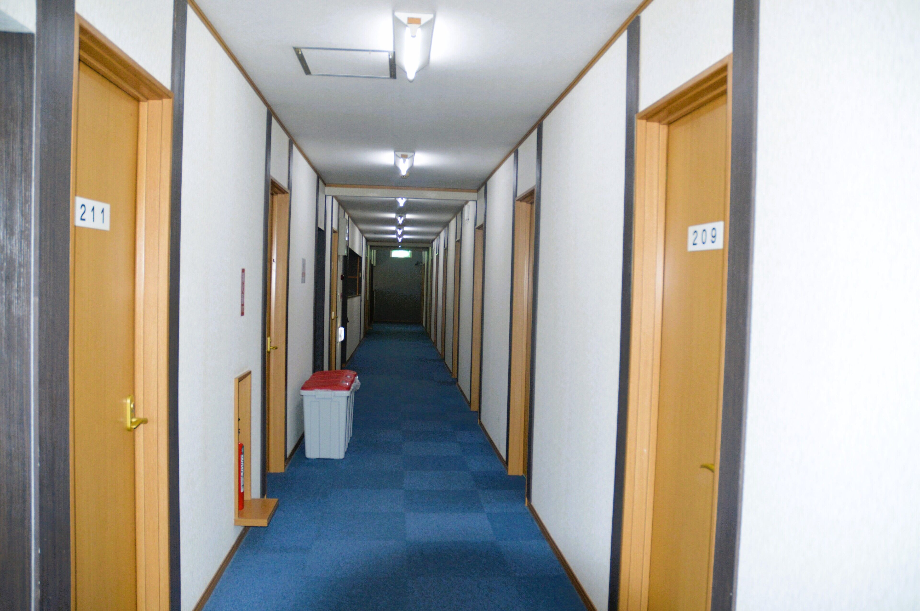 A long, narrow hallway with doors numbered 211 and 209, leading to rooms.