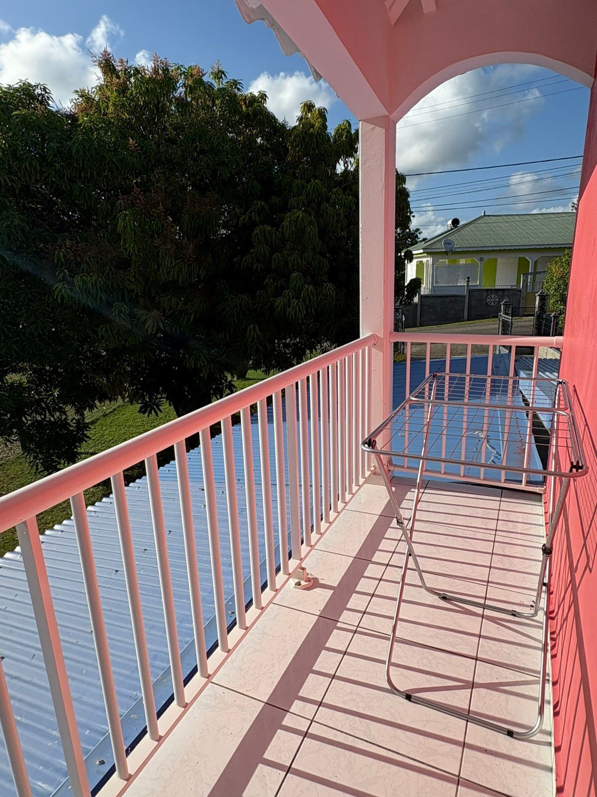 A balcony with a metal railing, a tiled floor, and a view of a body of water and greenery.