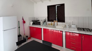 Een keuken met witte kasten, een zwarte tafel en een raam boven de gootsteen.