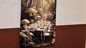 Luminária de parede com design vintage, posicionada acima de um quadro com cogumelos e uma mesa em cenário florestal.