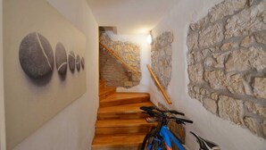 Un corridoio stretto con una scala in legno che conduce a un muro di pietra.