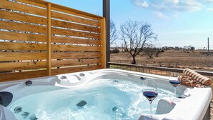 Un bain à remous avec deux verres de vin, une serviette et une vue sur un paysage aride.