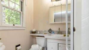 Et badeværelse med toilet, vask og skab.