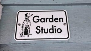 Skilt på en bygning med teksten 'Garden Studio' og en illustration af en hund.