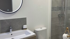 Ein modernes Badezimmer mit Waschbecken, Spiegel und Toilette in Weiß.